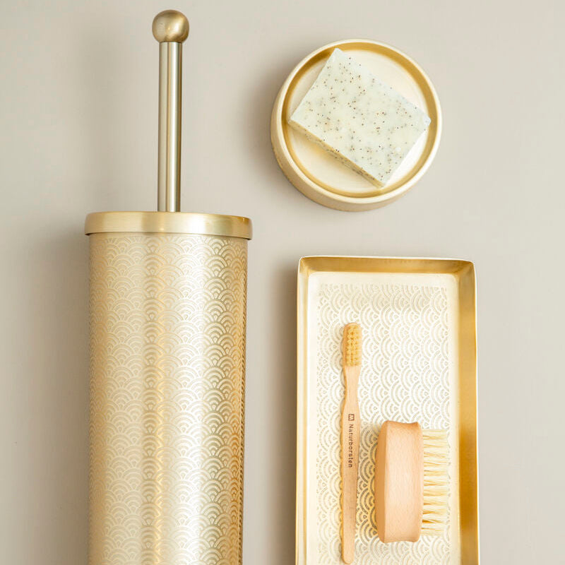 Bathroom accessories set with gold toilet brush holder, soap dish, and toothbrush holder on a beige background.