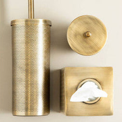 Brass toilet brush holder, cover, and tissue holder set against a white background