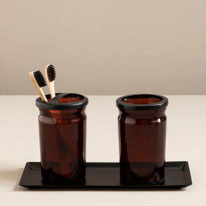Two brown jars with black lids on a black tray against a beige background