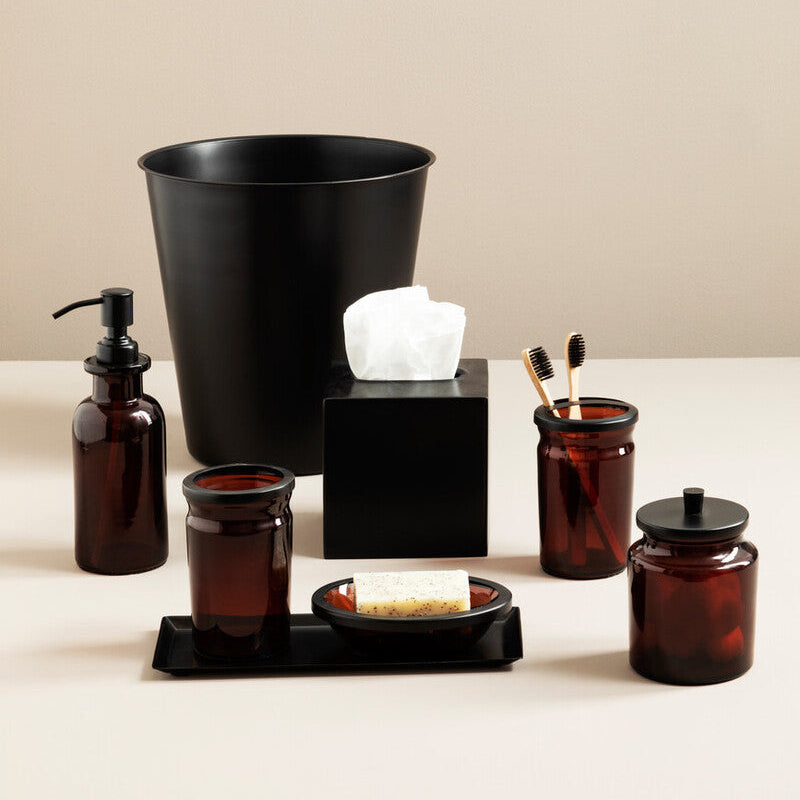 Bathroom accessories including a black trash can, brown bottles, and a tissue box on a beige background.