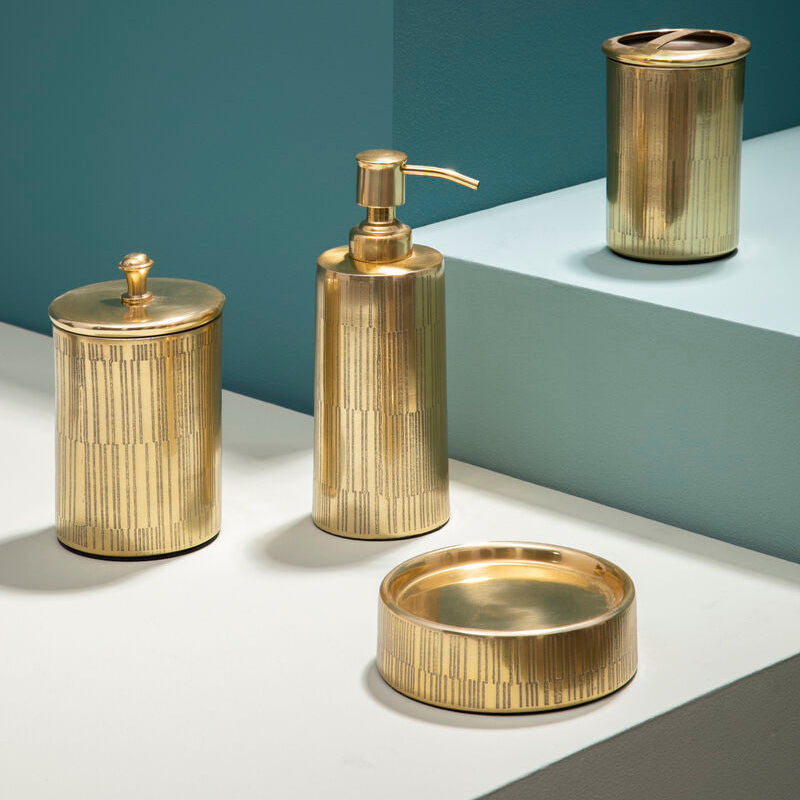 Set of gold bathroom accessories including a dispenser, jar, and bowl on a geometric background.