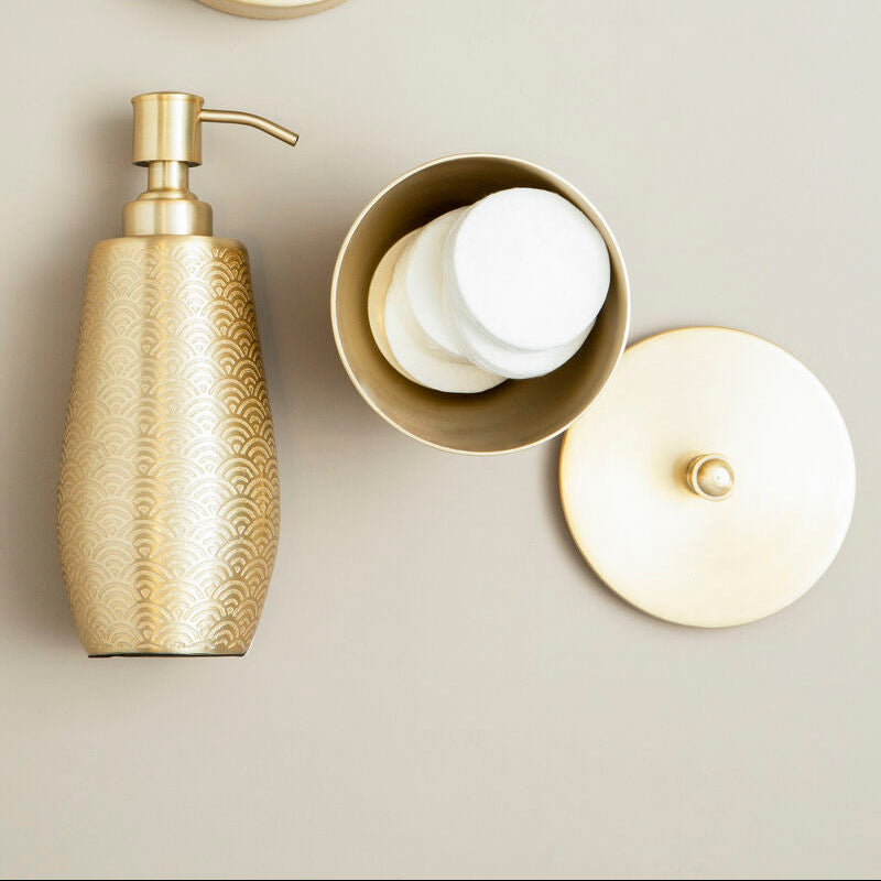 Gold soap dispenser and containers with lids on a neutral background