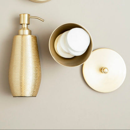 Gold soap dispenser and containers with lids on a neutral background
