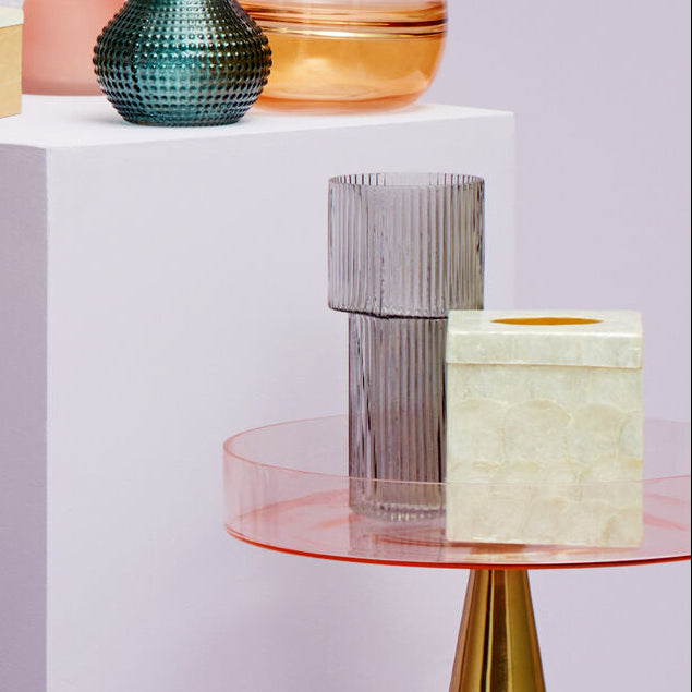 Collection of colorful vases on a table with a soft pink background