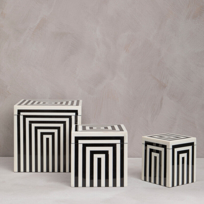 Three black and white striped cubes on a light gray background