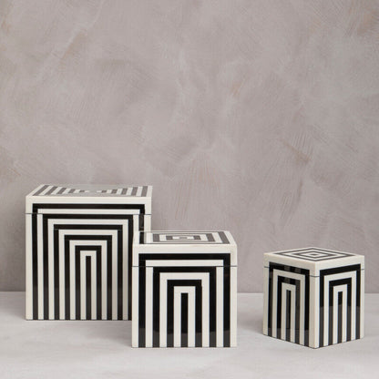 Three black and white striped cubes on a light gray background