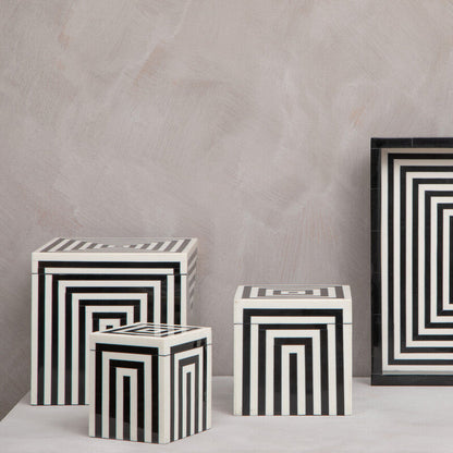Decorative black and white geometric containers on a neutral background