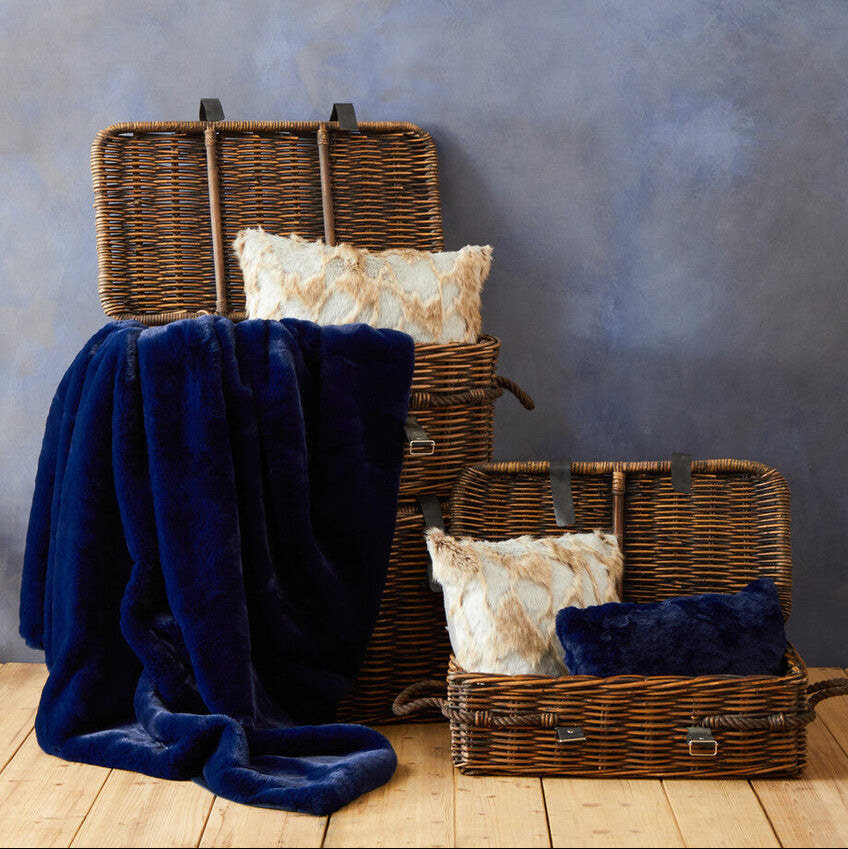 Wicker suitcases with blankets and pillows against a textured wall.