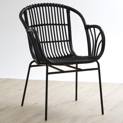 Black wicker chair on a light wooden floor with a white background