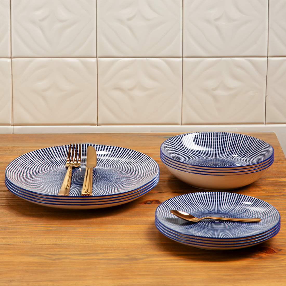 Set of blue and white patterned ceramic dishes on a wooden surface with a tiled wall background.