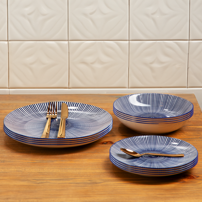 Set of blue and white patterned ceramic dishes on a wooden surface with a tiled wall background.