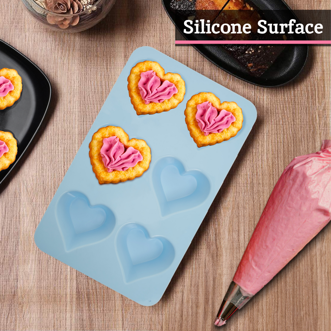 Silicone mold with heart shapes on a wooden surface with baking tools.