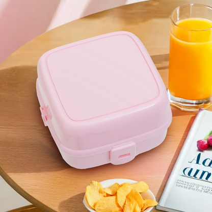 Pink lunch box on a table with snacks and juice