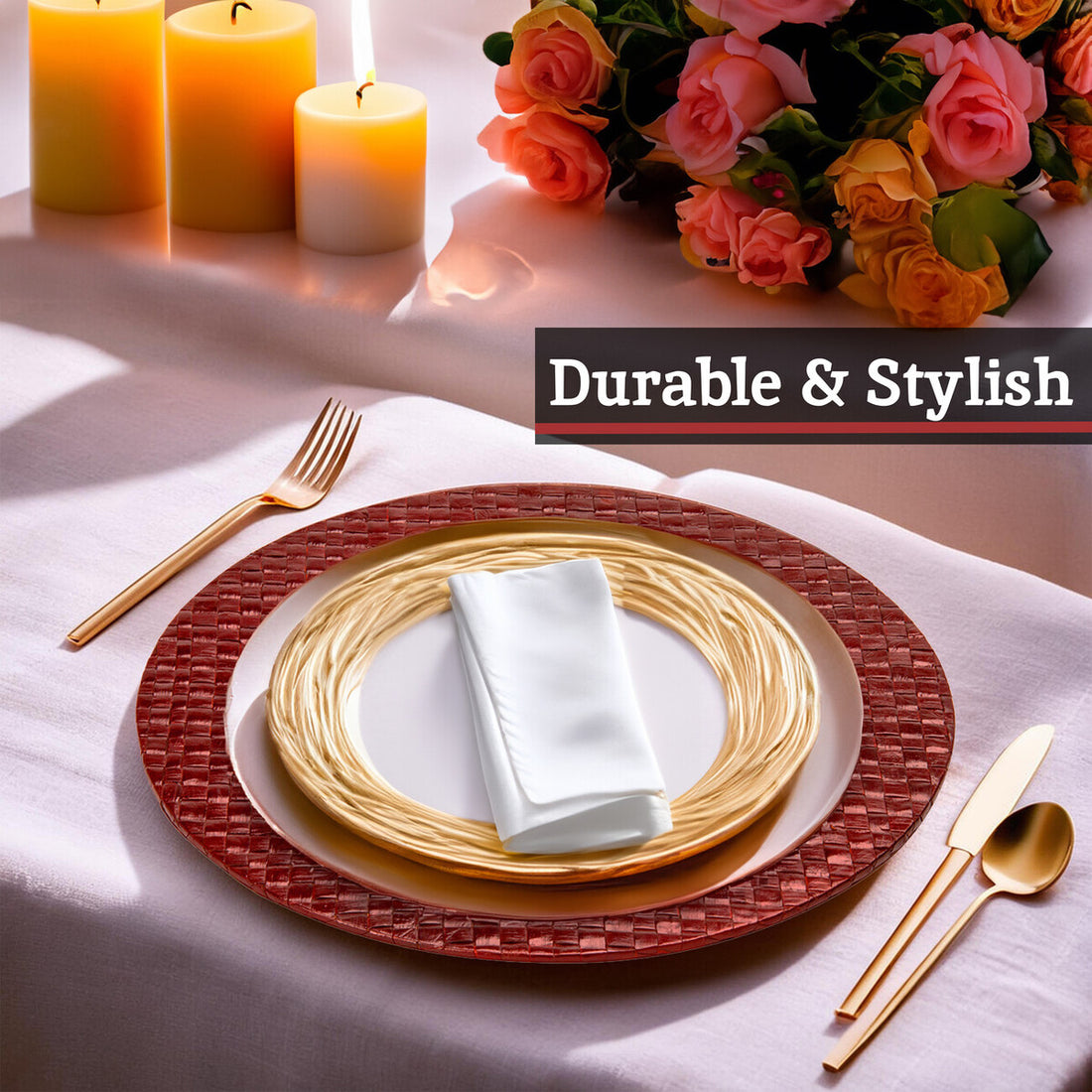 Table setting with red woven placemat, gold plates, white napkin, and cutlery on a white tablecloth with candles and flowers.