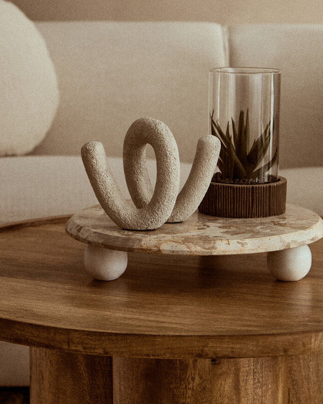 Decorative table with a sculpture and plant in a living room setting