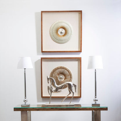 Two framed artworks on a wall above a glass console table with decorative items.