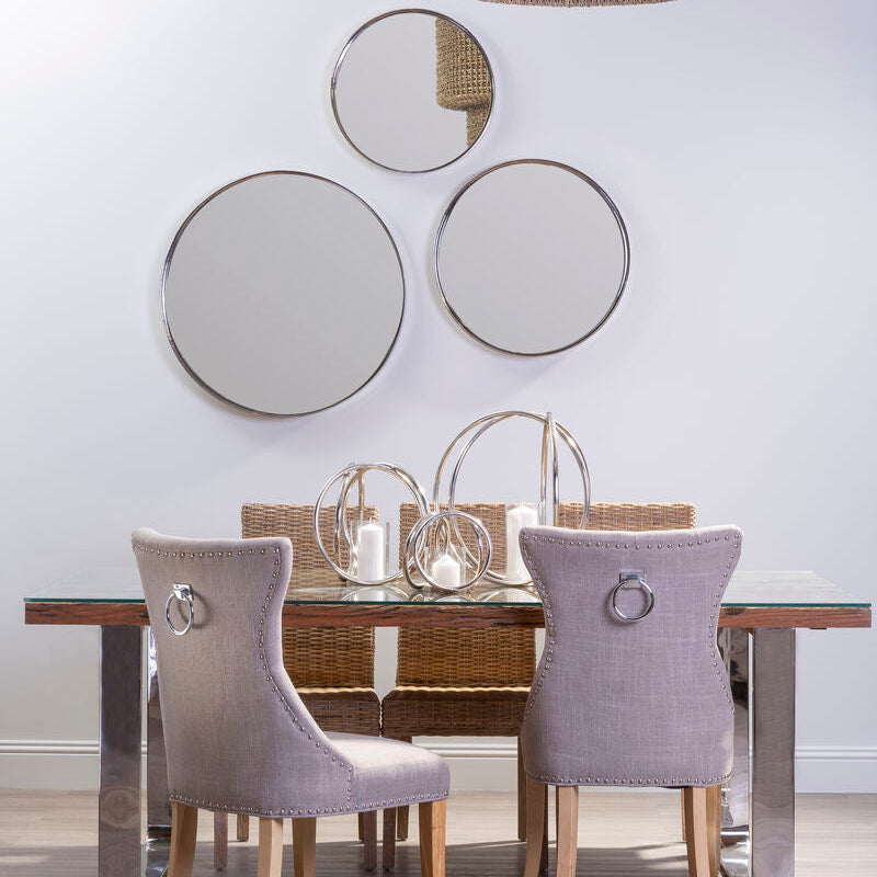 Dining room with a wooden table and gray chairs, featuring decorative mirrors on the wall.
