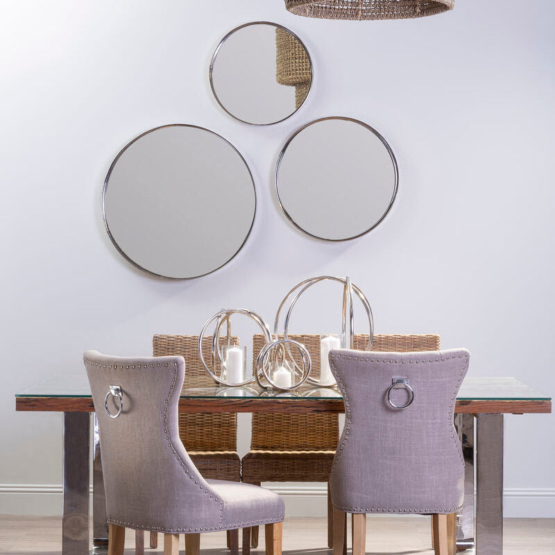 Dining room with a wooden table and gray chairs, featuring decorative mirrors on the wall.