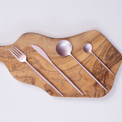 Wooden cutting board with silverware on a light gray background