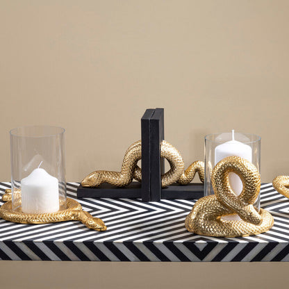 Decorative table setting with gold knot sculptures, candles, and a striped runner.