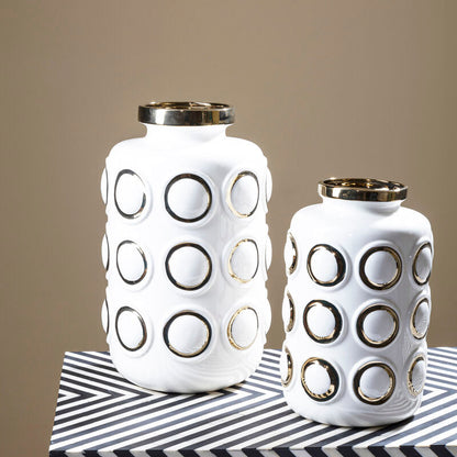 Two white ceramic vases with black circular patterns on a striped surface.