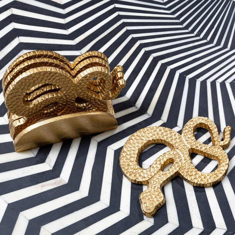 Gold elephant and snake figurines on a black and white striped surface