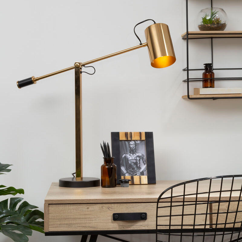 Desk with a lamp, photo frame, and bottles against a white wall.