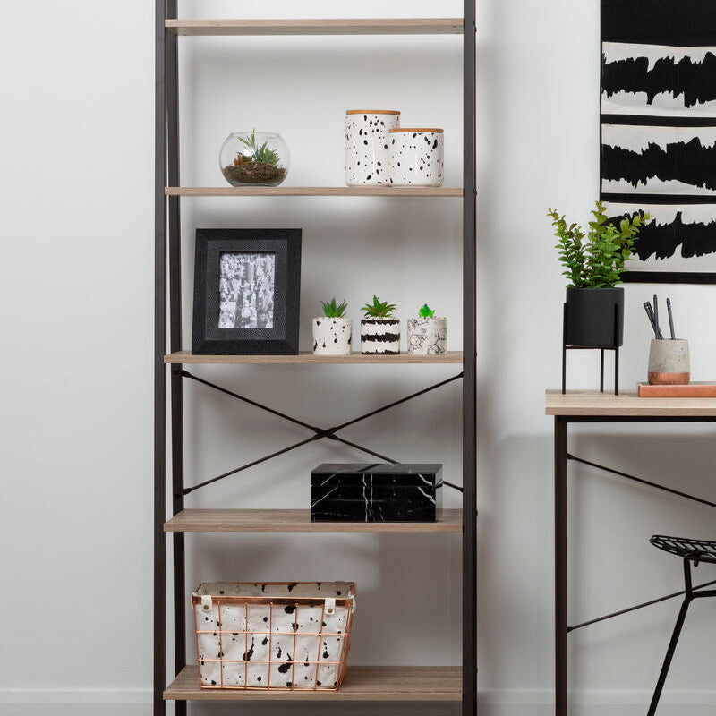 Tall bookshelf with decorative items in a room with a desk and wall art.