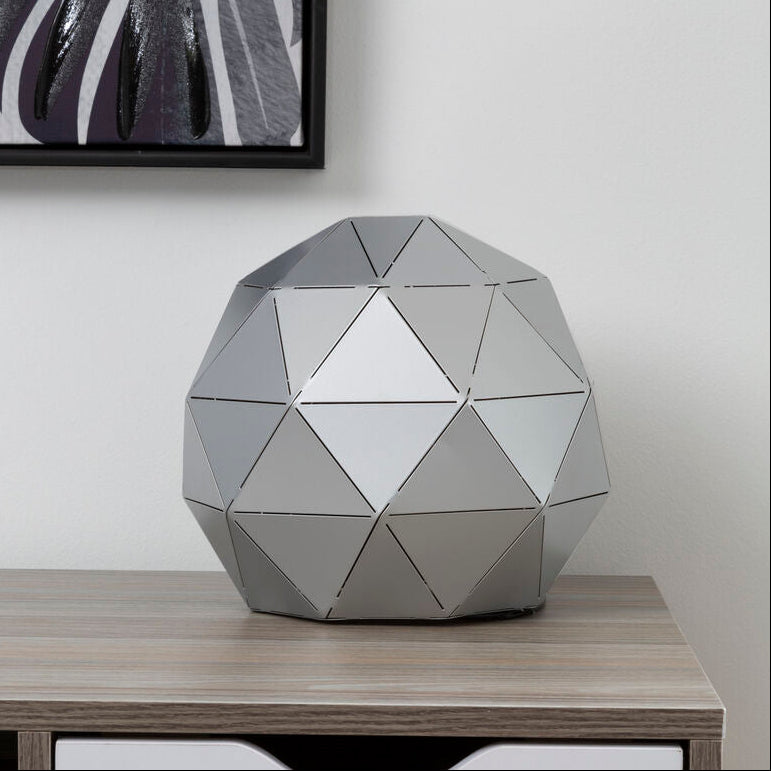 Geometrically patterned decorative object on a wooden shelf with a white drawer.