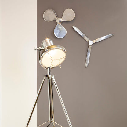 Floor lamp with propeller design on a wooden floor against a gray wall