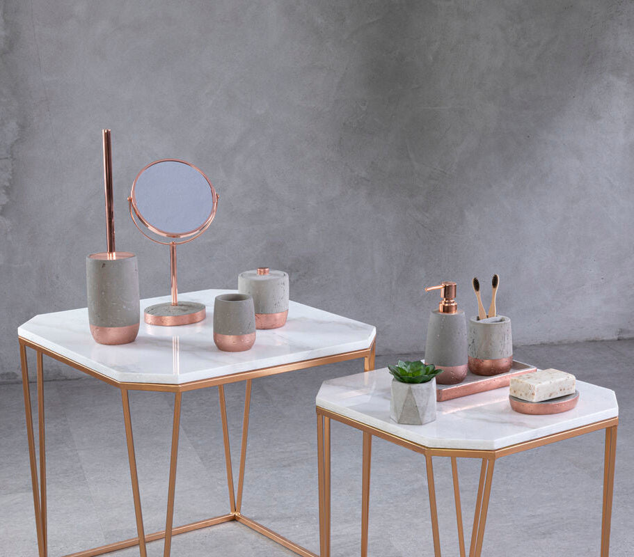 Decorative items on marble tables against a gray concrete wall