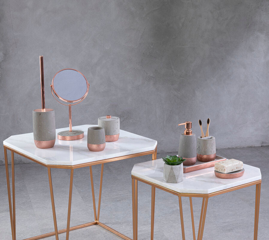 Decorative items on marble tables against a gray concrete wall