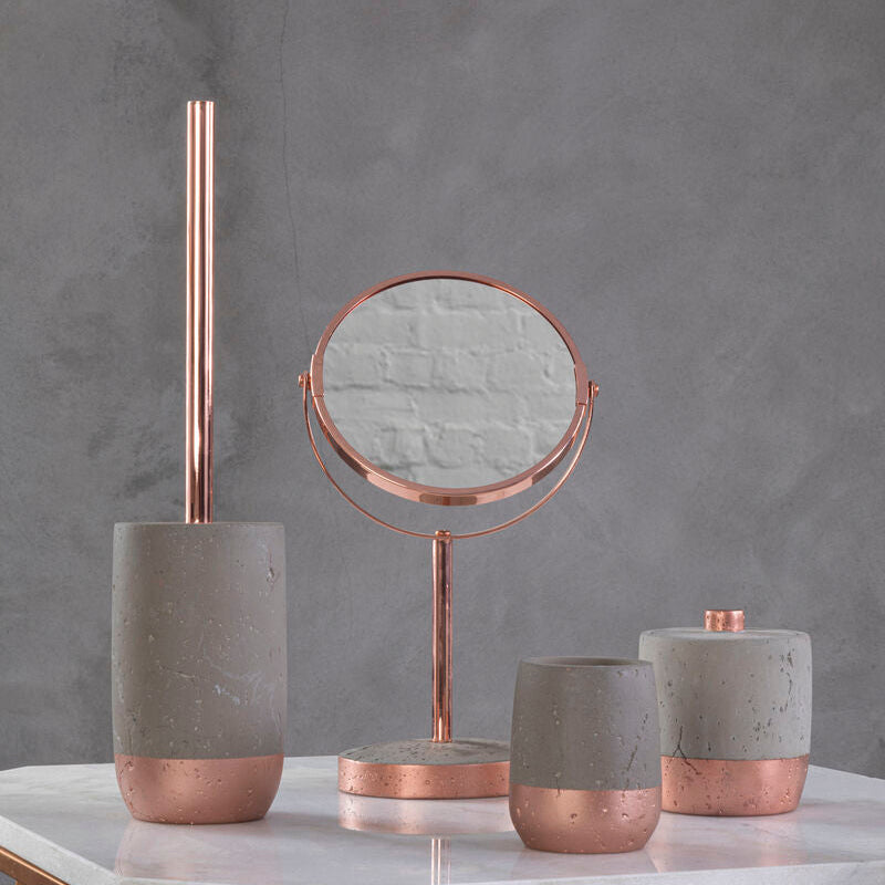 Decorative items including a mirror, candles, and a brush holder on a marble surface with a gray background.