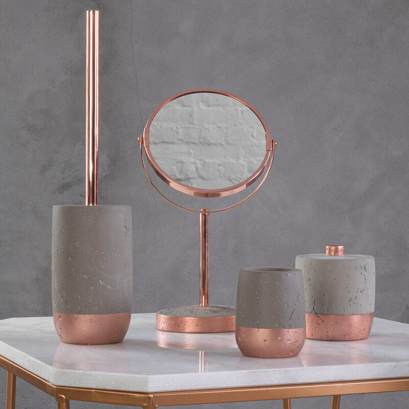 Decorative items including a mirror, candles, and a brush holder on a marble surface with a gray background.