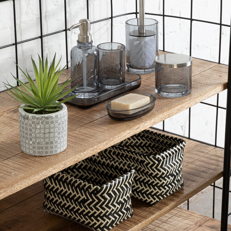 Bathroom shelf with toiletries, a plant, and baskets against a white brick wall.