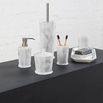 Bathroom accessories including a soap dispenser, toothbrush holder, and soap dish on a dark surface with a white brick wall background.