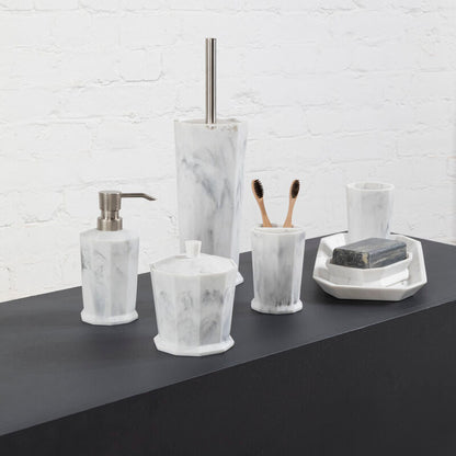 Bathroom accessories including a soap dispenser, toothbrush holder, and soap dish on a dark surface with a white brick wall background.